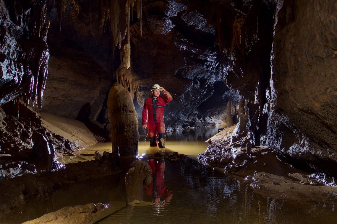 un spéléologue dans une grotte à rivière souterraine